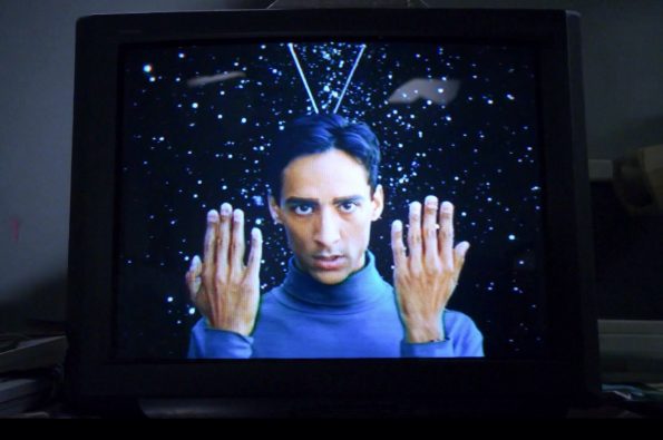 Abed, le héros de la série community est dans un vieux téléviseur en combinaison bleue avec des antennes sur la tête et les manis en l'air comme s'il tentait de communiquer par signes. Oui, il simule un extraterrestre. C'est Abed.